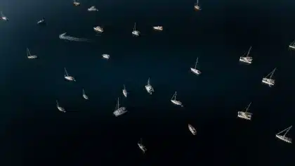 Schermo galleggiante illuminato sulla laguna veneziana con imbarcazioni disposte a anfiteatro al tramonto.