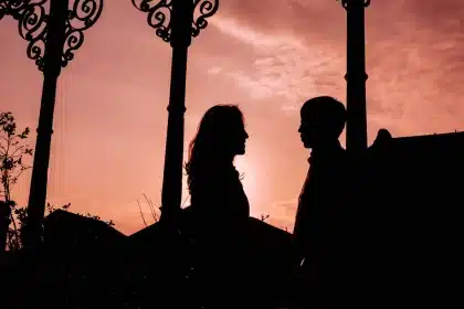 Coppia in silhouette che si abbraccia teneramente su sfondo di pagine di giornale sfocate