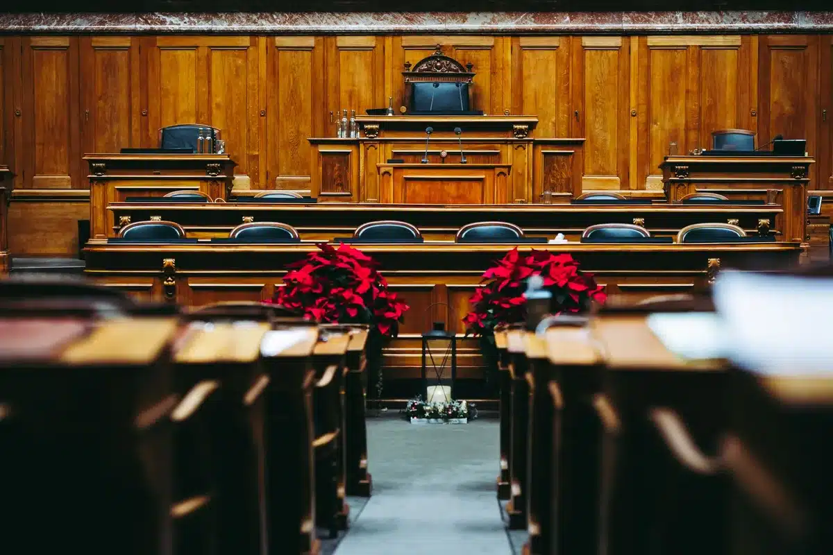 Avvocati in aula durante una discussione procedurale, fascicoli e documenti legali visibili