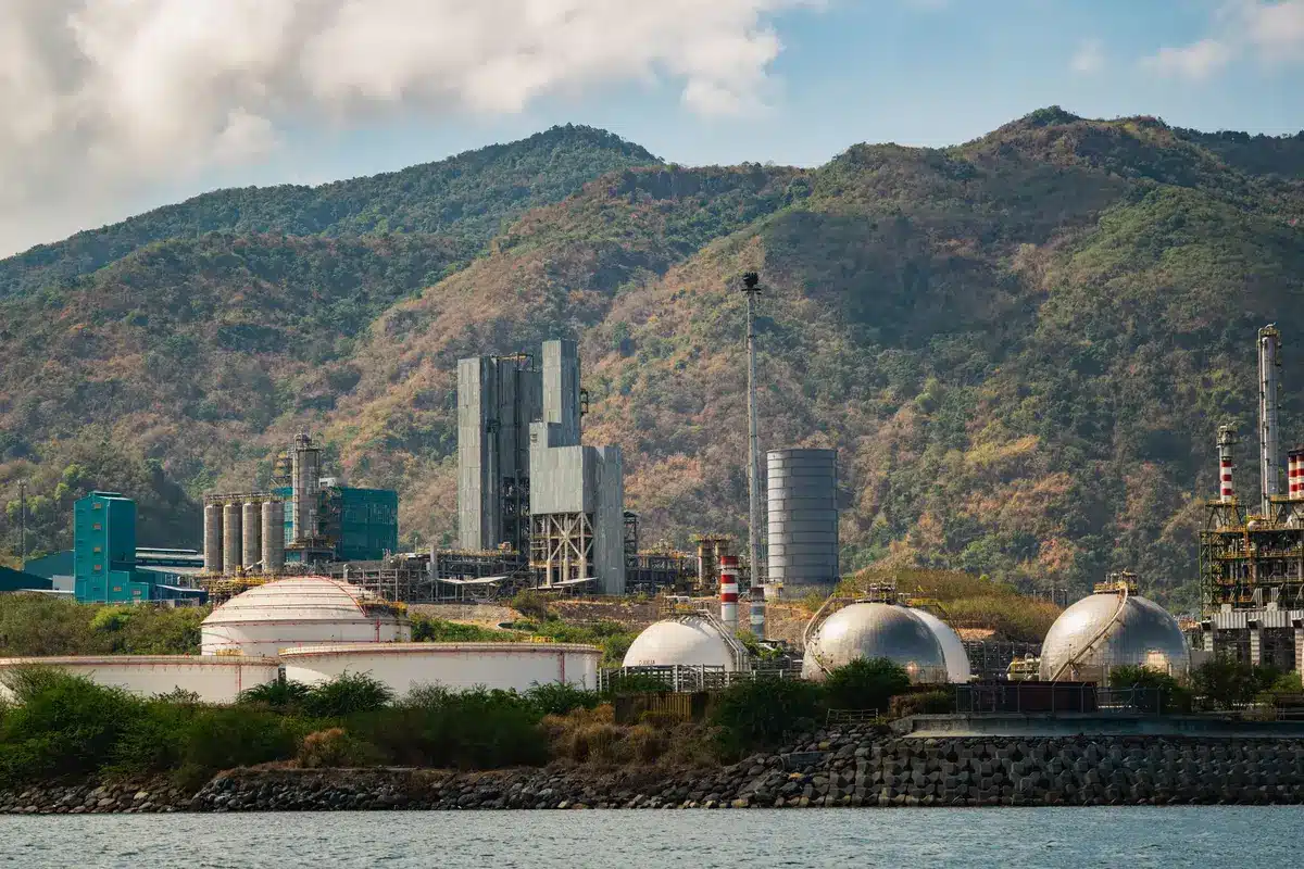 Stabilimento industriale con impianti produttivi e paesaggio naturale sullo sfondo