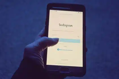 Mano di una persona anonima contro lo schermo di uno smartphone illuminato al buio, simboleggiando la censura algoritmic