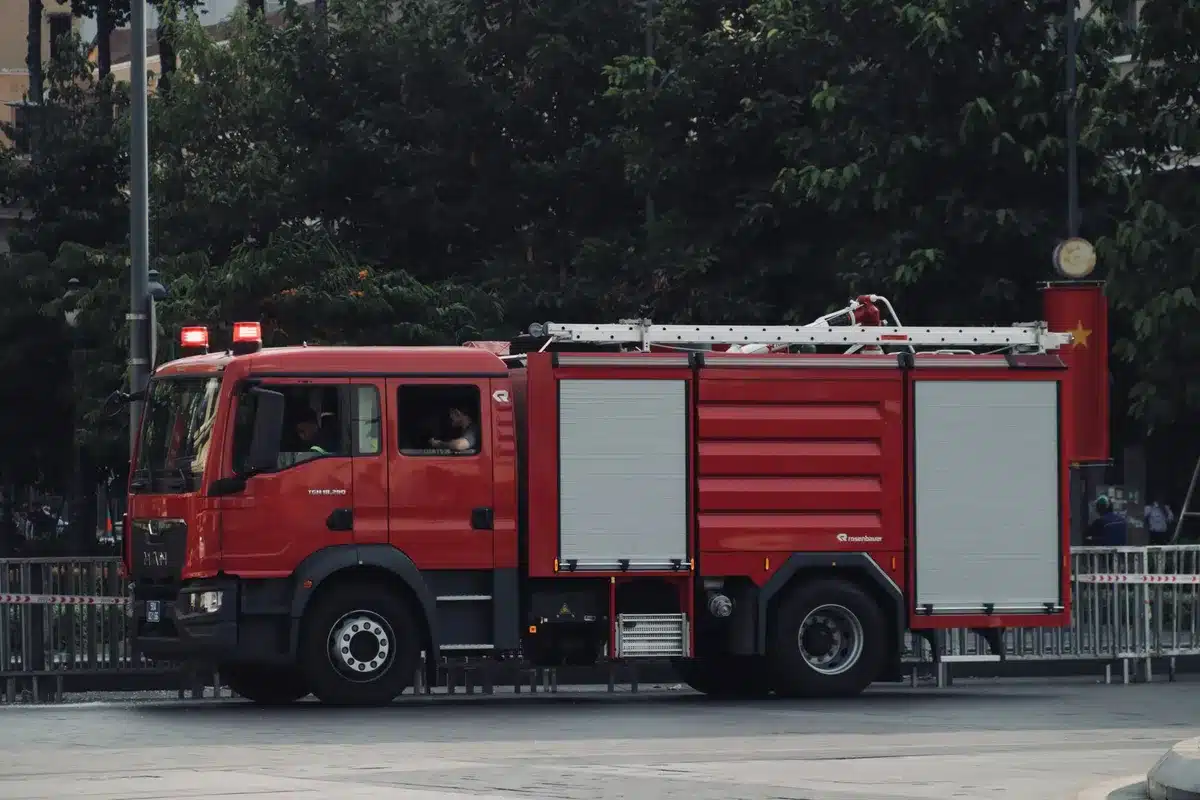 Magazzino in fiamme con vigili del fuoco e mezzi d'emergenza in intervento notturno