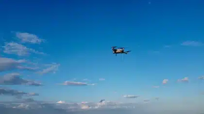 Droni in volo notturno su infrastrutture militari, con schermi radar in una sala operativa