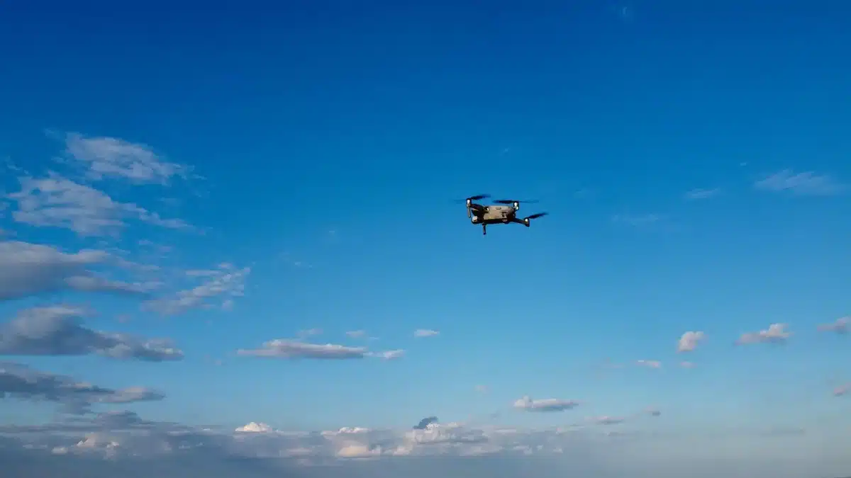Droni in volo notturno su infrastrutture militari, con schermi radar in una sala operativa