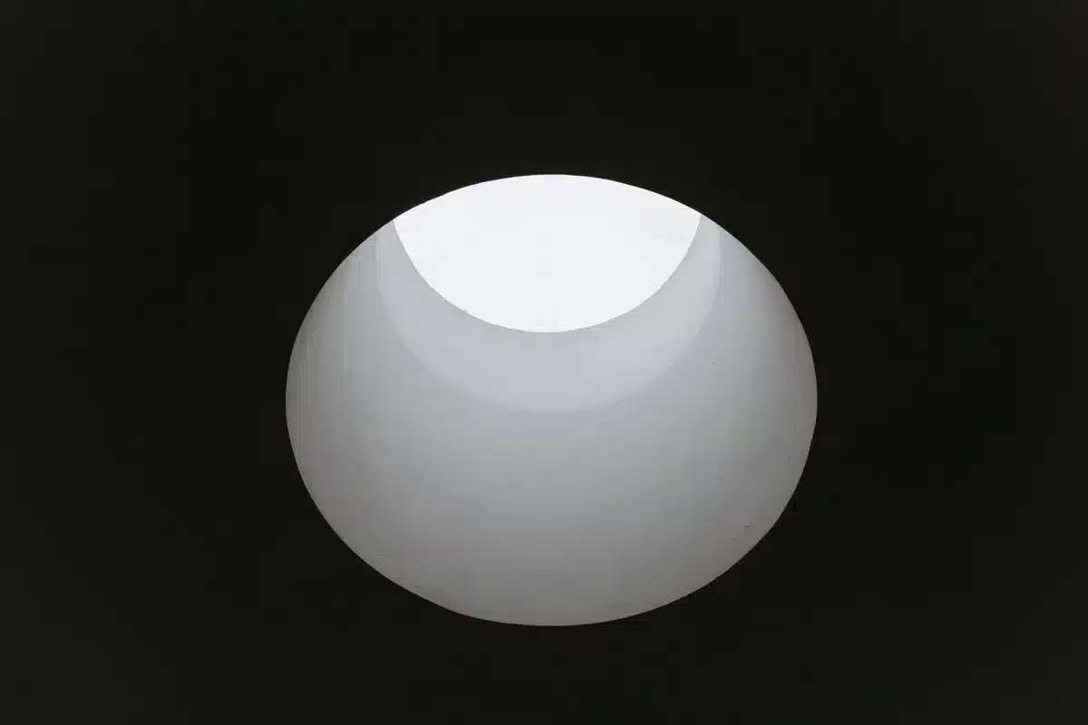 Scultura astratta in pietra con fori e vuoti che creano gioco di ombre e luce