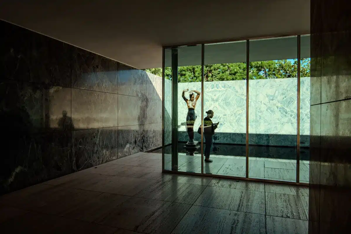 Scultura astratta in marmo nel cortile di un museo, con forme organiche e vuoti che dialogano con la luce naturale