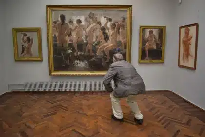 Sala d'asta con bidders che alzano la mano per offrire su un'opera d'arte esposta sul palco