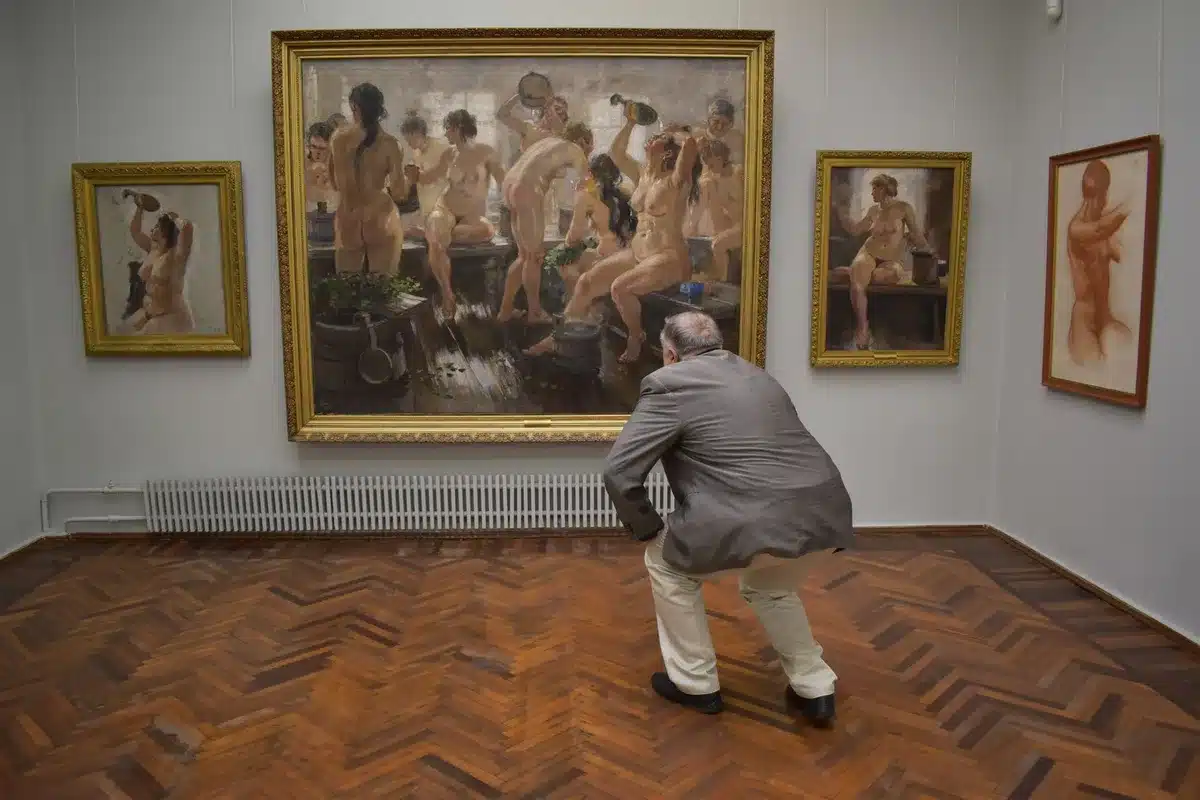 Sala d'asta con bidders che alzano la mano per offrire su un'opera d'arte esposta sul palco