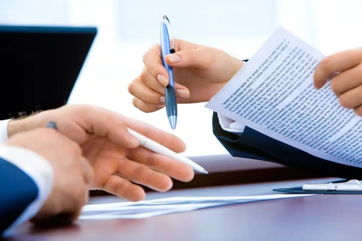 Mani anonime su documenti e calcolatrice su scrivania in ufficio