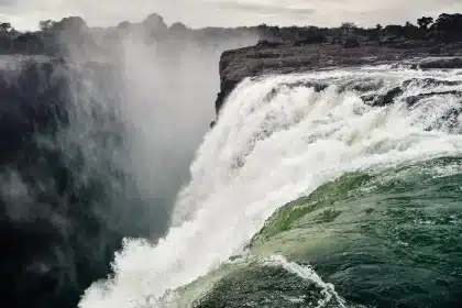 Una piena lampo scorre violentemente lungo un sentiero di canyon, trascinando detriti e acqua fangosa.