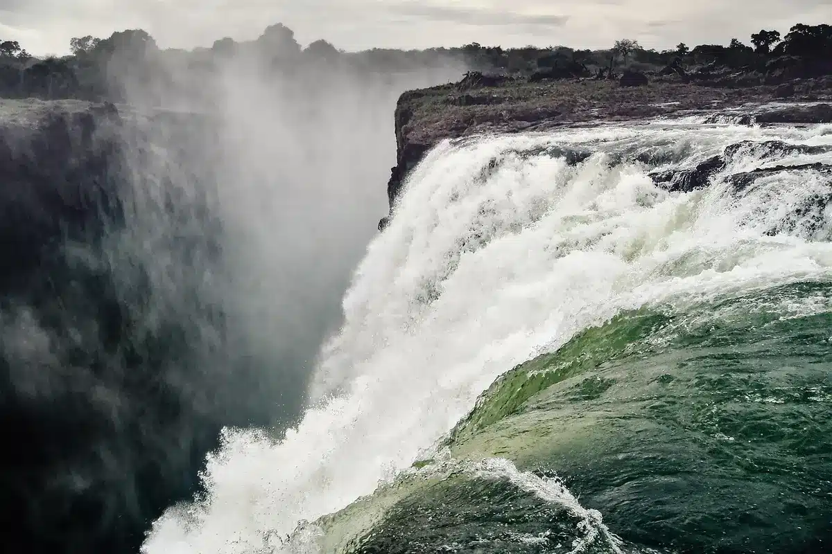 Una piena lampo scorre violentemente lungo un sentiero di canyon, trascinando detriti e acqua fangosa.
