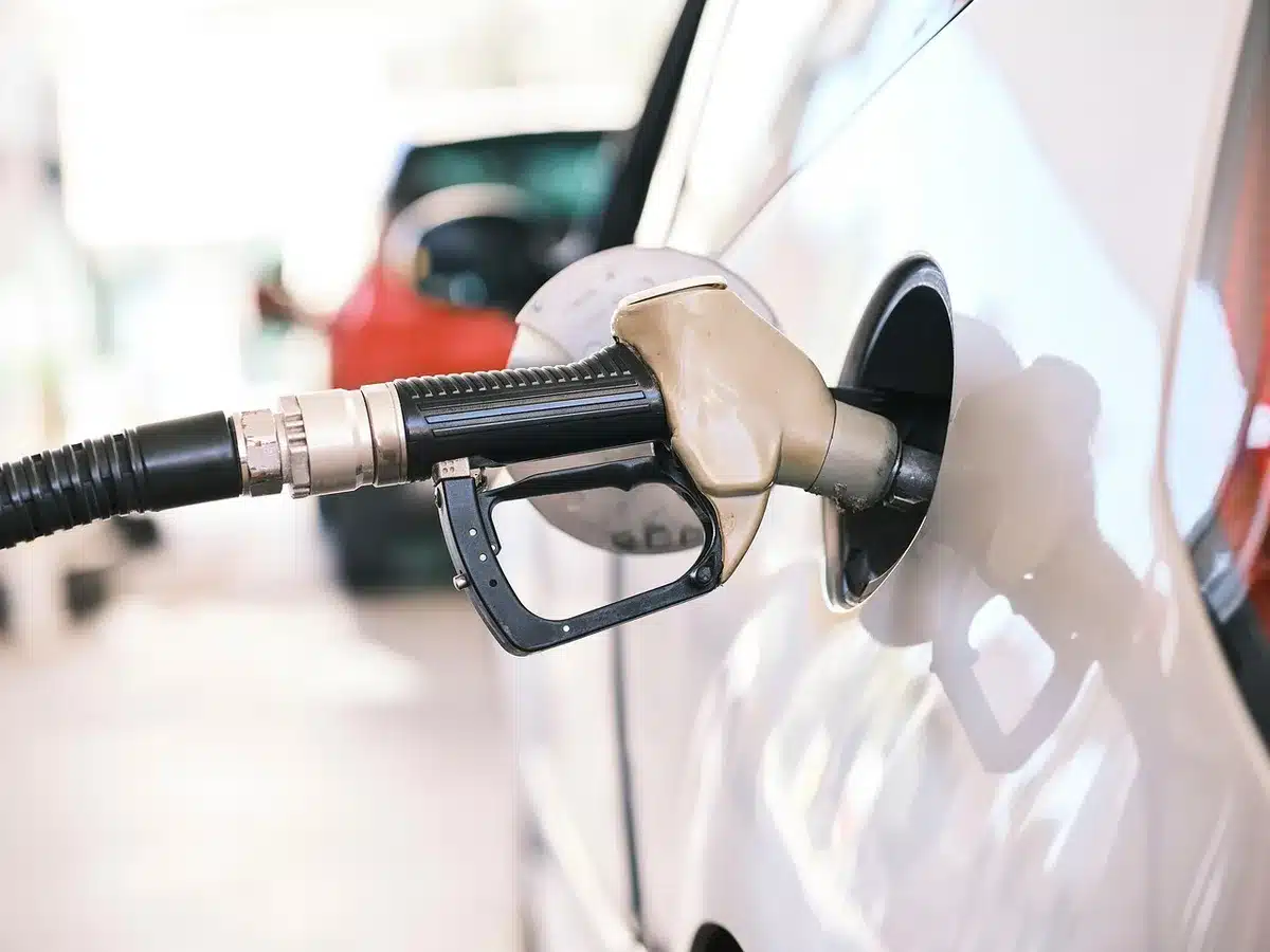 Auto in fila davanti a una pompa di benzina con prezzi visibili