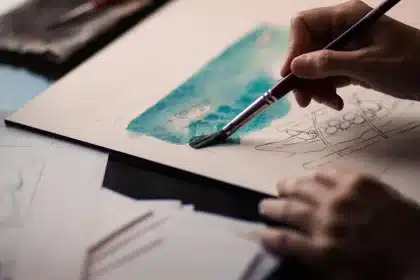 Studio con artista di spalle davanti a un quadro con forme astratte e colori naturali
