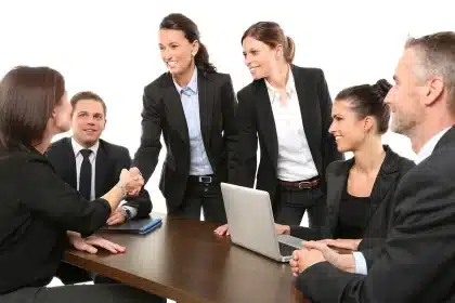 Tavolo di lavoro con mappe, laptop e poster in una sala civica, mani anonime che organizzano materiali