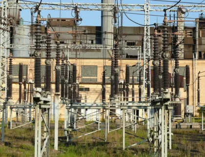 Recinzione e impianto elettrico anonimo al crepuscolo con luci di emergenza sullo sfondo