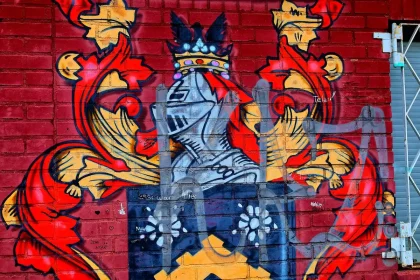 Artista dipinge murale colorato su muro di mattoni in un piccolo centro urbano