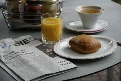 Mani che tengono un quotidiano aperto con una vignetta e una tazza di caffè accanto