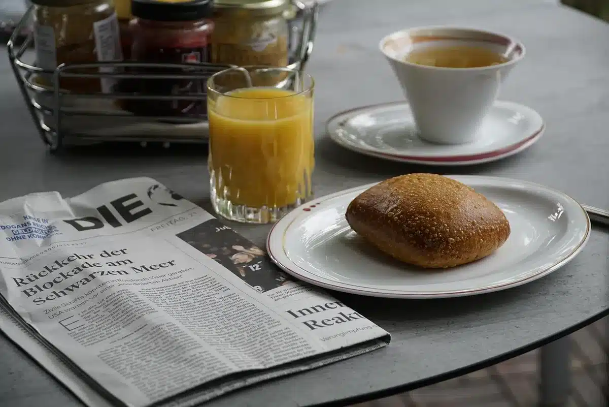 Mani che tengono un quotidiano aperto con una vignetta e una tazza di caffè accanto