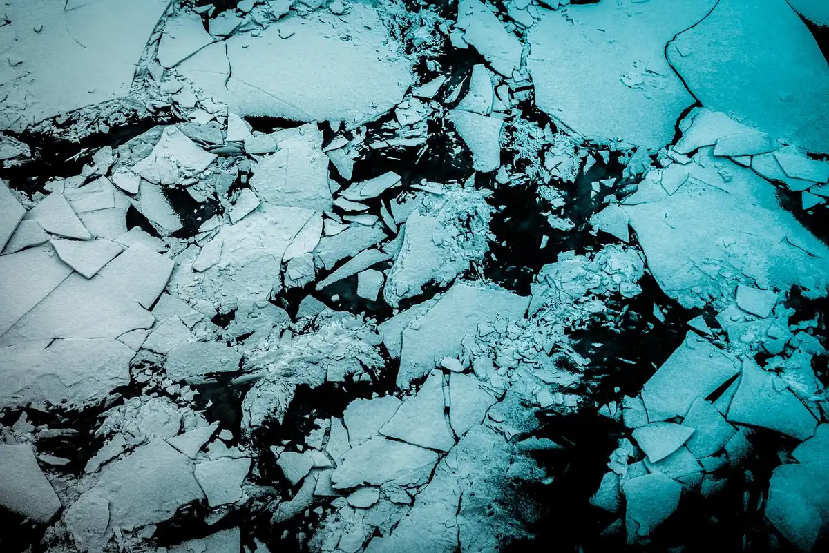Plateau antartico con una stazione scientifica anonima e una nave vicino all'orizzonte