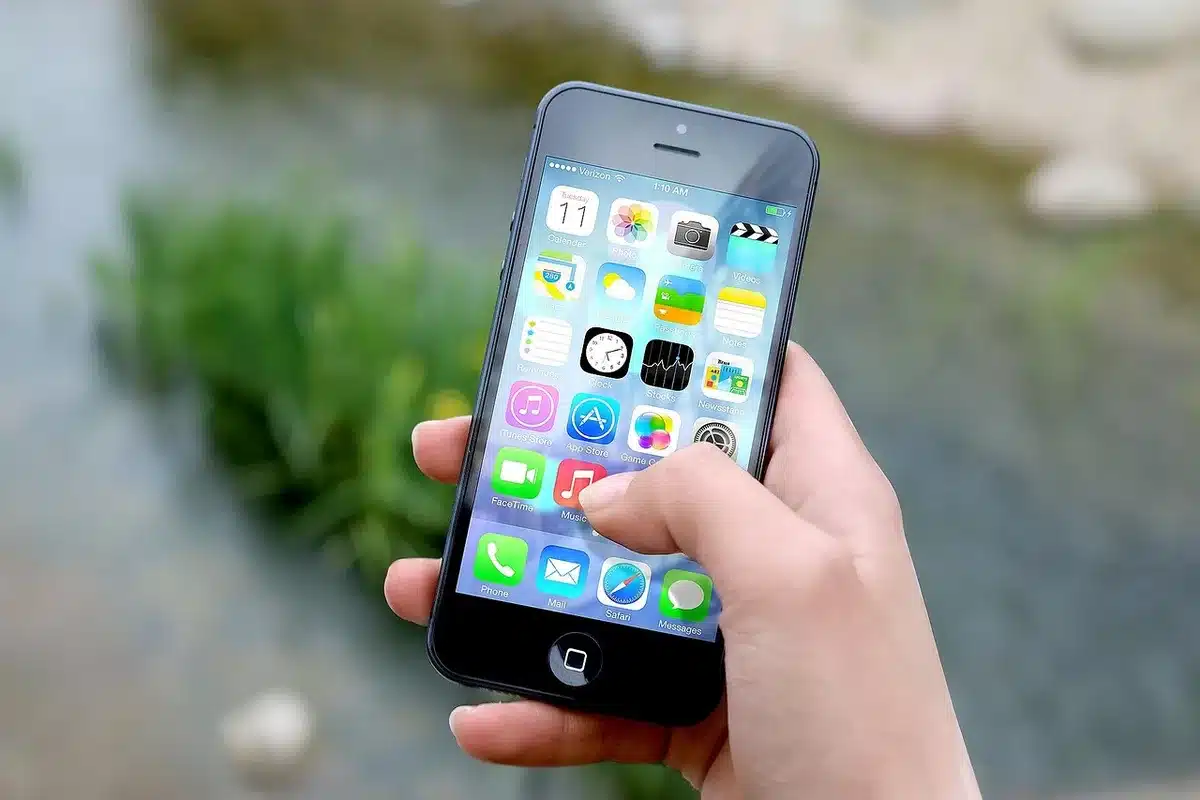 Mani anonime che tengono uno smartphone davanti a uno schermo con cartelle digitali