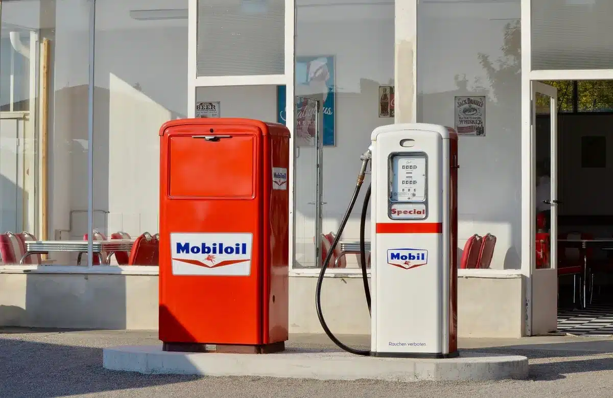 Prezzi alla pompa mostrati su un display di distributore con mano che rifornisce
