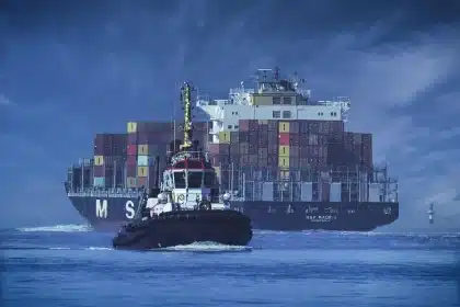 Mani anonime indicano container e silhouette di un'auto elettrica in un porto urbano