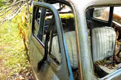 Strada cittadina vuota con auto danneggiata e documenti sparsi, figura di spalle