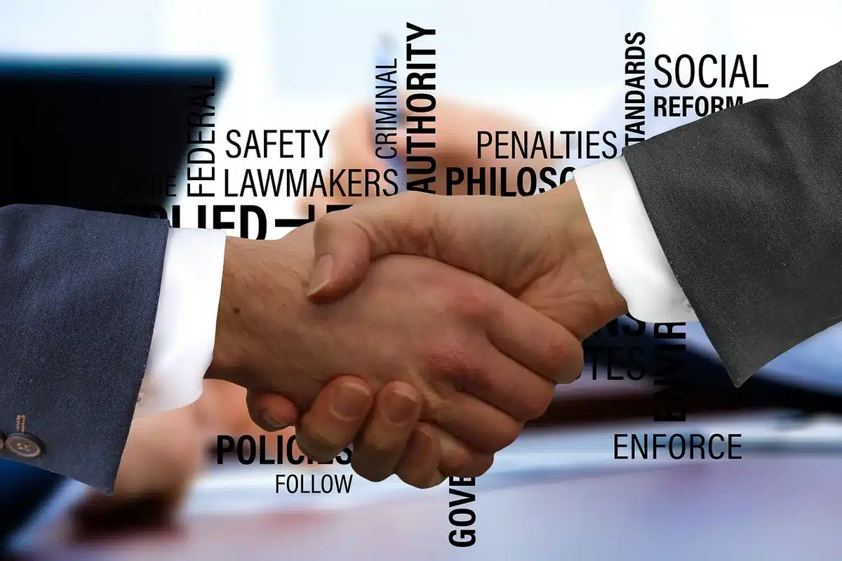Due figure anonime che si stringono la mano davanti a documenti elettorali, simbolo degli scambi fra alleati